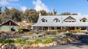 A large house with a covered porch, a small shed, and a well-maintained garden with rocks and plants. - Girraween Country Inn (Eukey)