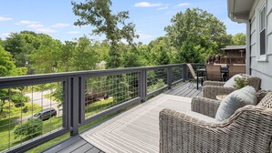 Una terraza techada al aire libre con mobiliario de mimbre y vistas a un paisaje verde.