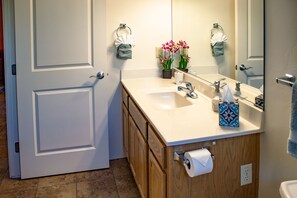 Une salle de bain avec une porte blanche, des meubles en bois, un lavabo beige et un miroir.