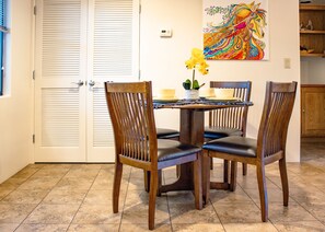 Un coin repas avec une table ronde, quatre chaises en bois et un vase rempli de fleurs jaunes.