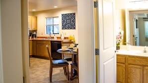 A kitchen with wooden cabinets, a dining table with chairs, and a window with blinds. - Eclectic boho style apartment in the heart of West Sedona (Sedona)
