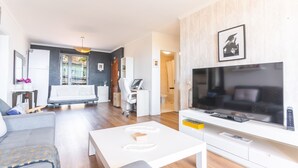 Un salon moderne comprenant un canapé, une table basse, un téléviseur et un bureau.