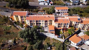 Vue aérienne d’un ensemble résidentiel comprenant plusieurs immeubles d’appartements, chacun étant doté de toits couverts de tuiles rouges et de balcons.