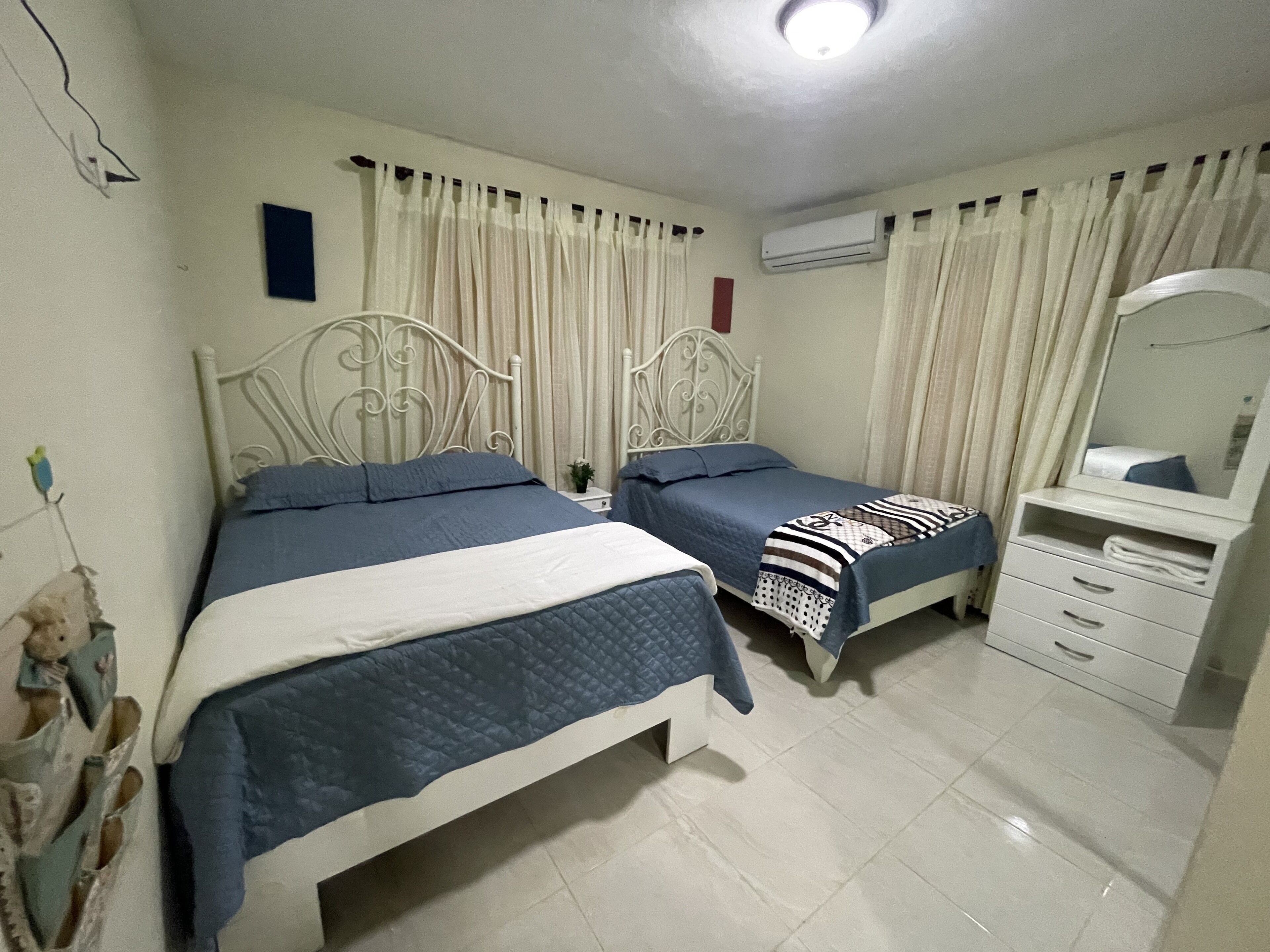 A bedroom with two beds, a dresser, and an air conditioning unit.