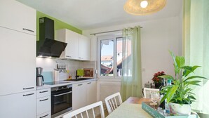 Une cuisine moderne avec des meubles blancs, un four encastré et un coin repas comprenant une table et des chaises.