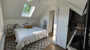 A bedroom with a bed, a ceiling fan, a skylight, a door, and a window. - Charming spacious 1933 newly renovated private home. Walk to trails (Highlands)