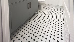 Une salle de bain avec un meuble-lavabo gris, un miroir rond, des toilettes blanches et un rideau de douche.