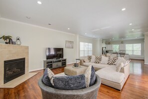 A spacious living room with a fireplace, a large sectional sofa, and a television.