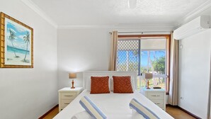 Habitación de hotel con una cama grande, dos mesitas de noche, un cuadro y una ventana con vistas.