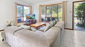 Sala de estar con sofá, televisión y una mesa de centro de madera.