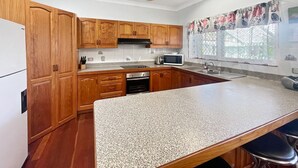 A kitchen with wooden cabinets, a granite countertop, a microwave, and a ceiling fan. - Arcadia Gardens (Arcadia)