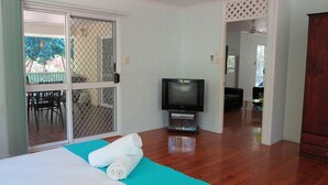 Ein Zimmer mit Bett, Fernseher und einer Schiebetür zu einem Außenbereich.