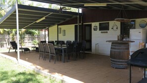 Une terrasse extérieure dotée d’un espace repas couvert, d’une barrique en bois et d’un réfrigérateur.