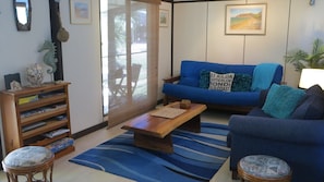 Una sala de estar con un sofá azul, una mesa de centro de madera y una estantería.