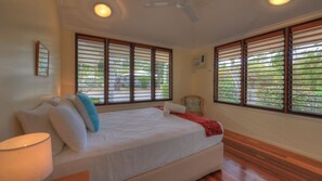 A bedroom with a bed, a chair, and large windows with blinds. - Lemonade (Arcadia)