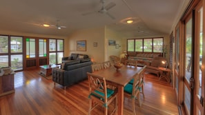 A spacious living area with a wooden dining table, cushioned seating, and large windows with blinds. - Lemonade (Arcadia)