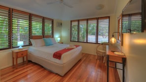 A bedroom with a bed, wooden floor, windows with blinds, a ceiling fan, and a bedside lamp. - Lemonade (Arcadia)