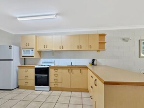 A kitchen with wooden cabinets, a microwave, a stove, and a sink.