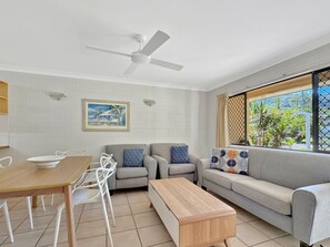 A modern living room with a sofa, chairs, a coffee table, and a dining table.