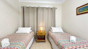 A hotel room with two beds, a nightstand with a lamp, and a framed picture on the wall.