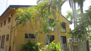 A yellow building with multiple windows, a balcony, and a wooden fence. - Casual Lodge Unit 4 short walk to Nelly Bay Beach (Nelly Bay)