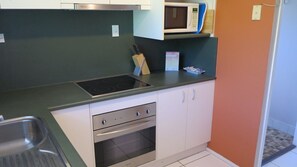 Une cuisine compacte équipée d’un four à micro-ondes, d’une cuisinière, d’un four et d’un bloc à couteaux.