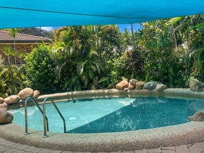 A swimming pool with a stone border, surrounded by tropical plants and rocks. - Arcadia Beach Unit 4 (Arcadia)