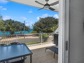 A balcony with a table and chairs, a ceiling fan, and a view of a swimming pool and trees. - Arcadia Beach Unit 4 (Arcadia)