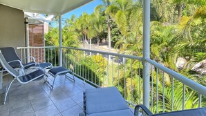 A balcony with two lounge chairs and a view of palm trees. - Island Magic Townhouse 5 (Arcadia)
