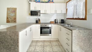 A modern kitchen with white cabinets, a built-in oven, a microwave, and a coffee maker. - Island Magic Townhouse 5 (Arcadia)