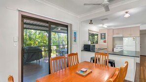 Enjoy casual dining in this kitchen and dining area, featuring a stove, microwave, and refrigerator, with a sliding door leading to a covered patio.