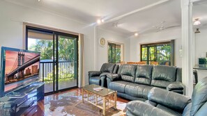 Relax in this stylish living room with a sofa, coffee table, and large sliding glass door leading to a lush outdoor area.