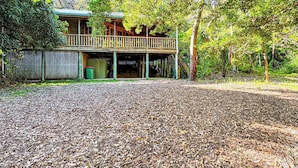 A wooden cabin with a balcony, surrounded by trees and a leaf-covered ground. - Kameruka (Arcadia)