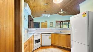 A kitchen with wooden cabinets, a white refrigerator, a dishwasher, and a stove. - Kameruka (Arcadia)
