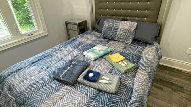 Un lit bien fait, avec une couvre-lit à motifs, des oreillers et des couvertures pliées.