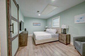 Een slaapkamer met een bed, nachtkastjes, een stoel, een dressoir en een schilderij aan de muur.