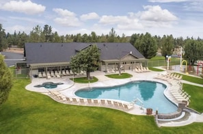 A large outdoor swimming pool with a curved design, surrounded by lounge chairs and a covered seating area.