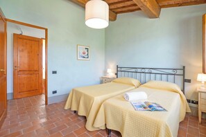A room with two beds, a wooden door, a ceiling light, and a wall-mounted picture. - Francigena 6, Castelfiorentino, Italy (Castelfiorentino)