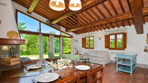 A dining area with a wooden table set for two, a sofa, and a window with a view of greenery. - Francigena 6, Castelfiorentino, Italy (Castelfiorentino)
