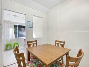 A room with a wooden table and four chairs, a window with curtains, and a door with a sign.