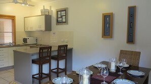 A kitchen with a microwave, a sink, and a dining area set with plates, glasses, and a candle.