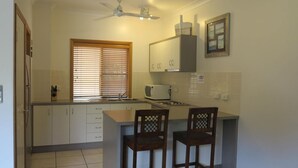 A kitchen with a microwave, a sink, wooden chairs, and a ceiling fan. - Sol Y Olas Sun & Waves (Arcadia)