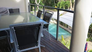 A glass-top table with chairs on a balcony overlooking a pool. - Sol Y Olas Sun & Waves (Arcadia)