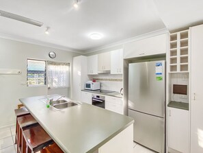 A modern kitchen with a central island, stainless steel appliances, and white cabinetry.