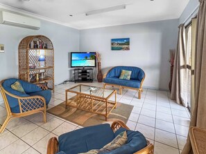 A living room with two blue sofas, a coffee table, a TV, and a bookshelf.