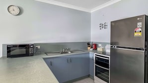 A modern kitchen with a built-in microwave, sink, and stainless steel refrigerator. - Magnetic Shores Unit 2 (Arcadia)