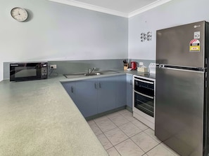 A modern kitchen with a built-in microwave, sink, and stainless steel refrigerator. - Magnetic Shores Unit 2 (Arcadia)