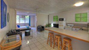 Una cocina moderna con barra, una mesa de comedor y un sofá en la sala de estar contigua.