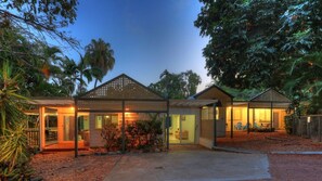 Una casa moderna con un porche cubierto, un pequeño jardín y vistas a los árboles circundantes.