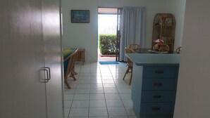 A room with a dining area, a blue cabinet, and a view of a garden through a door. - Magnetic Shores Unit 3 (Arcadia)